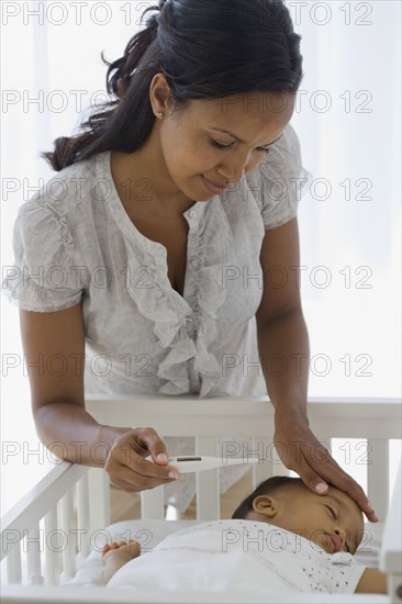 African American mother checking baby's temperature