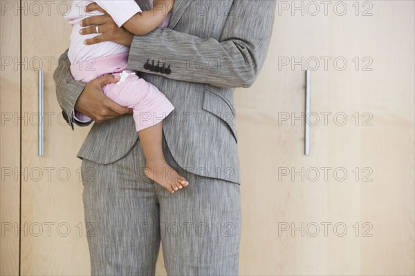 African American businesswoman holding baby