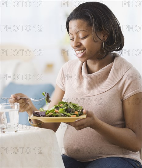 Pregnant African American woman eating salad