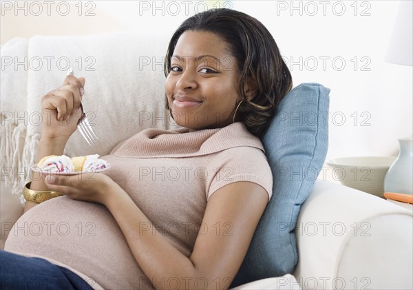 Pregnant African American woman eating cake