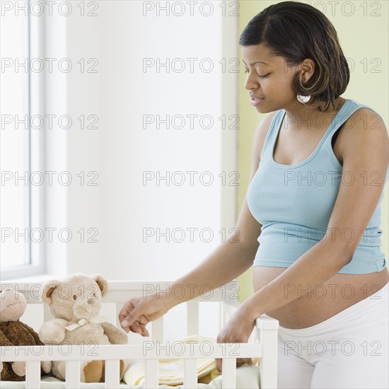 Pregnant African American woman looking at crib