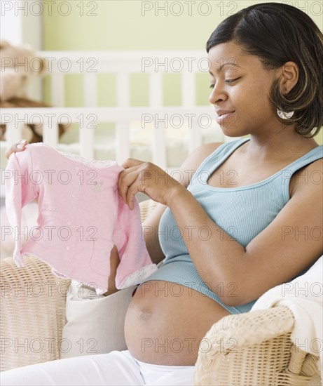 Pregnant African American woman holding baby clothes