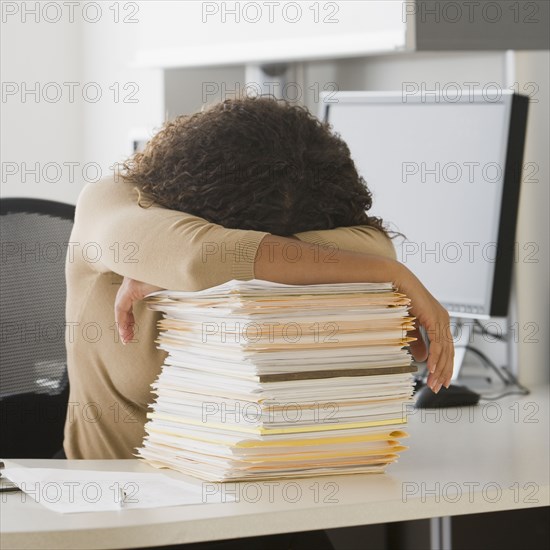 African businesswoman leaning on stack of paperwork