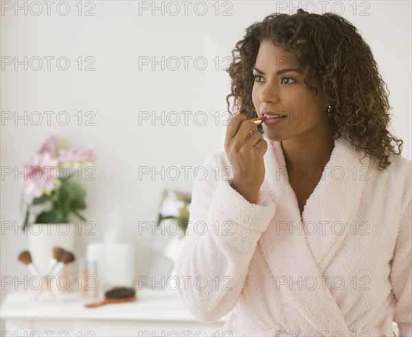 African woman applying lipstick