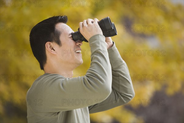 Asian man looking through binoculars