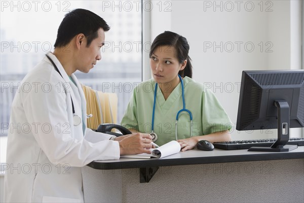 Asian doctors talking at desk