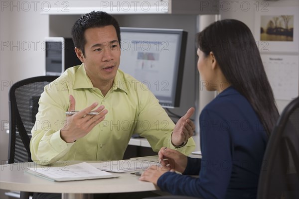 Asian businessman talking to coworker