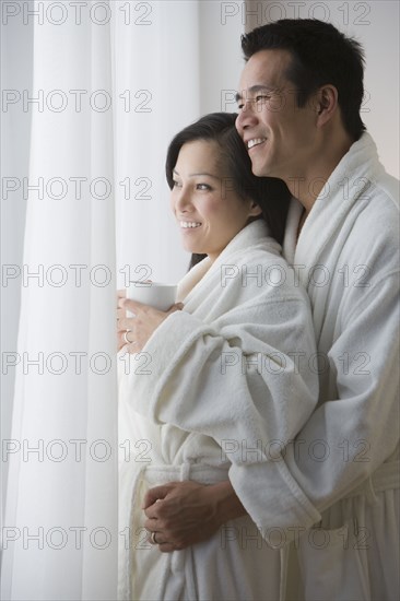 Asian couple in bathrobes hugging