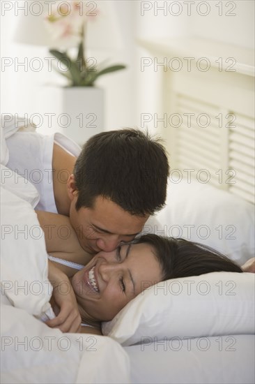Asian man kissing wife on cheek