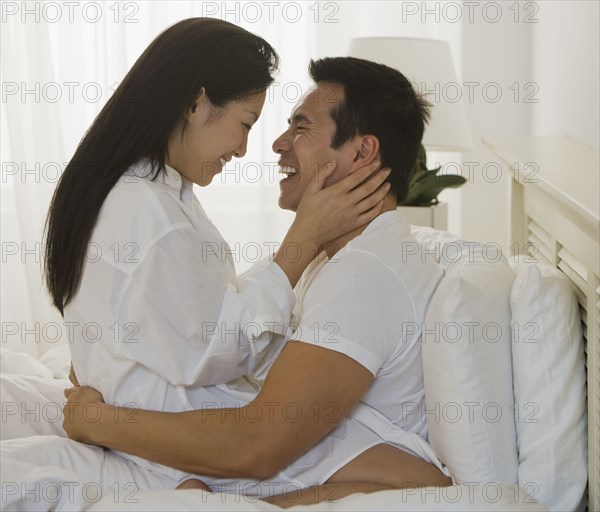 Asian couple hugging in bed