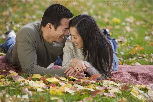 Asian couple laying on blanket