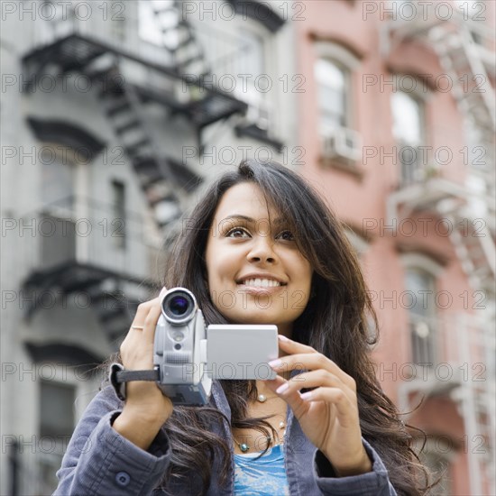 Mixed Race woman holding video camera