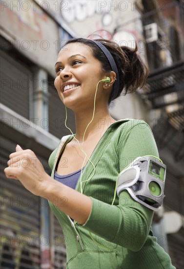 Mixed Race woman wearing headphones and jogging