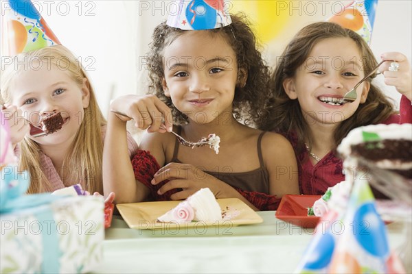 Multi-ethnic girls eating birthday cake