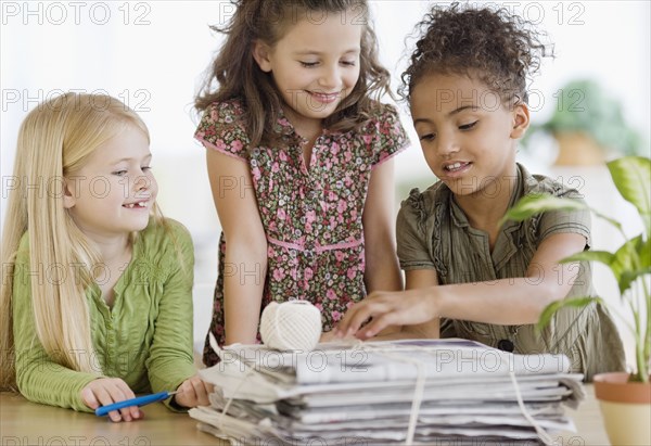 Multi-ethnic girls bundling newspapers