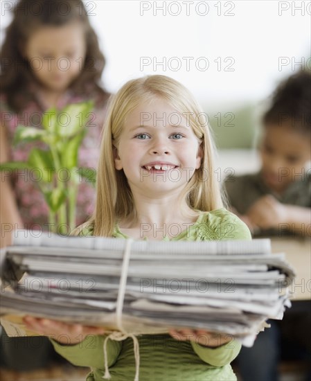 Girl holding bundle of newspapers