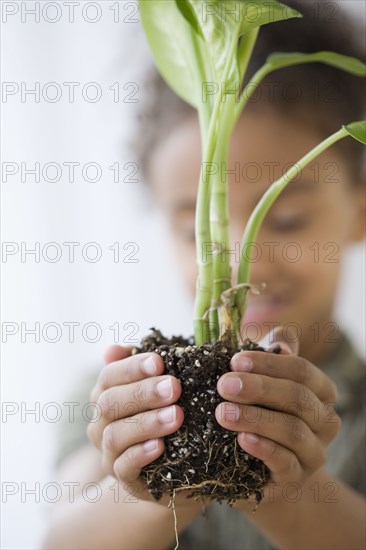 Mixed Race girl holding plant