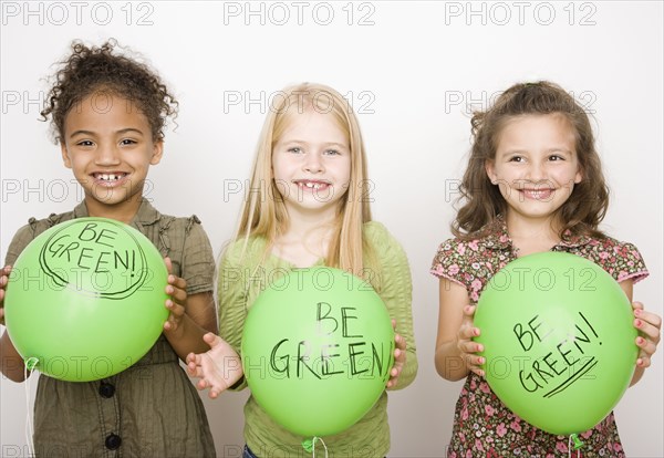 Multi-ethnic girls holding green balloons