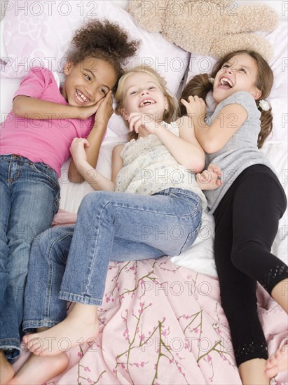 Multi-ethnic girls laying on bed