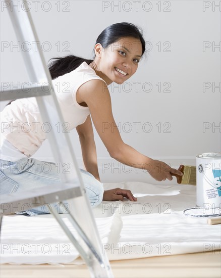 Pacific Islander woman painting baseboard