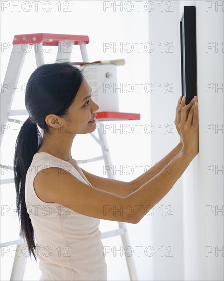 Pacific Islander woman hanging picture