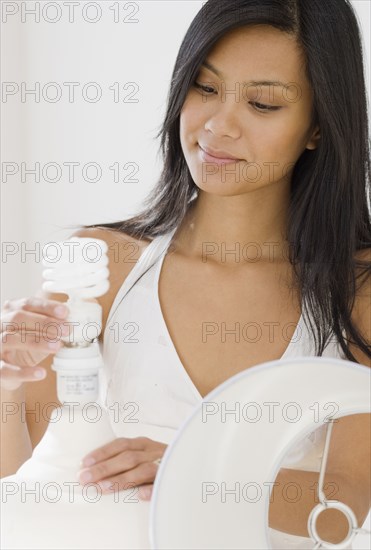 Pacific Islander woman replacing light bulb