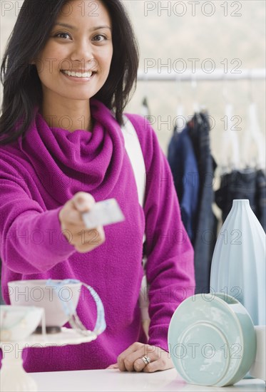 Pacific Islander woman paying at boutique with credit card