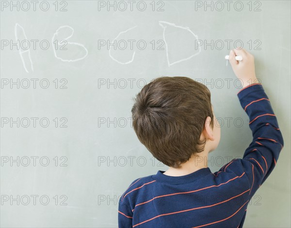 Hispanic boy writing on blackboard