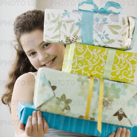 Hispanic girl holding stack of gifts