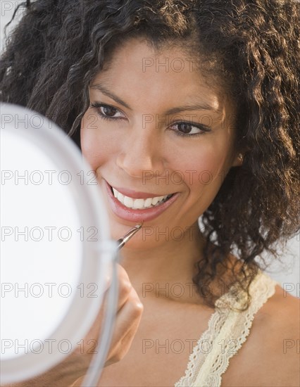 African woman applying lip gloss