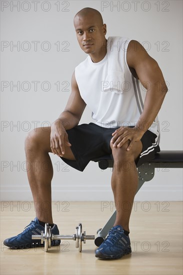 African man sitting on weight bench