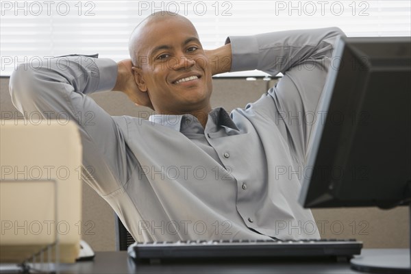 African businessman with hands behind head