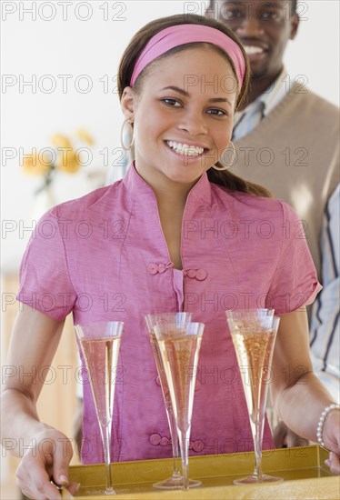 African woman carrying tray of champagne