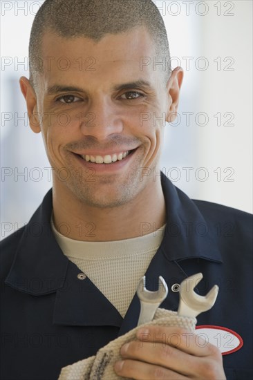 Hispanic male mechanic holding wrenches