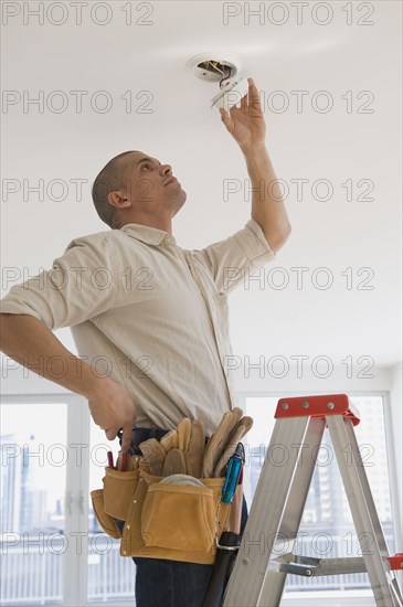 Hispanic male electrician fixing looking at wiring