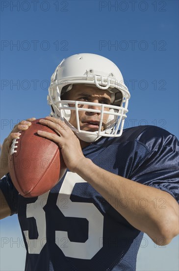 Hispanic male football player throwing ball