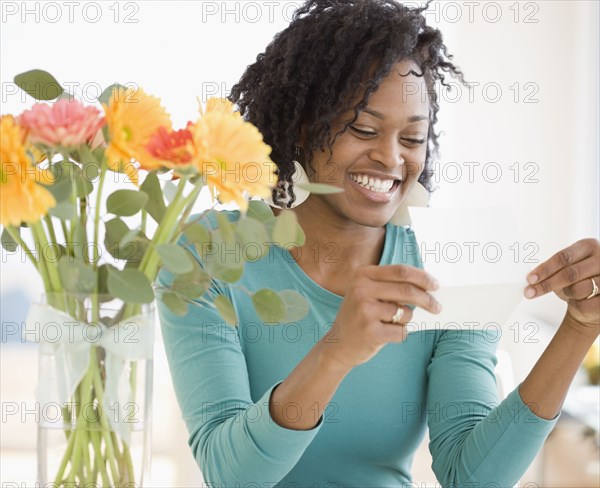 African woman reading card next to flowers