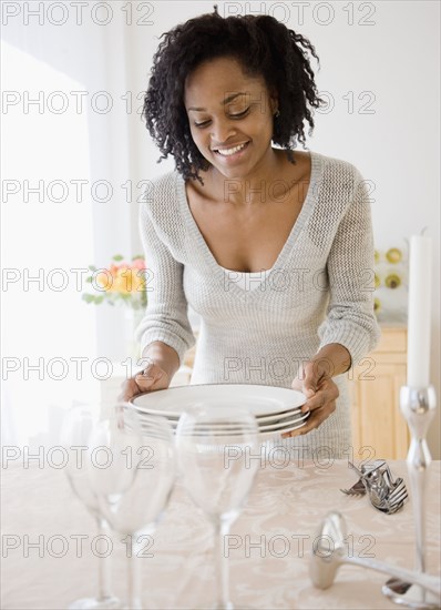 African woman carrying stack of plates