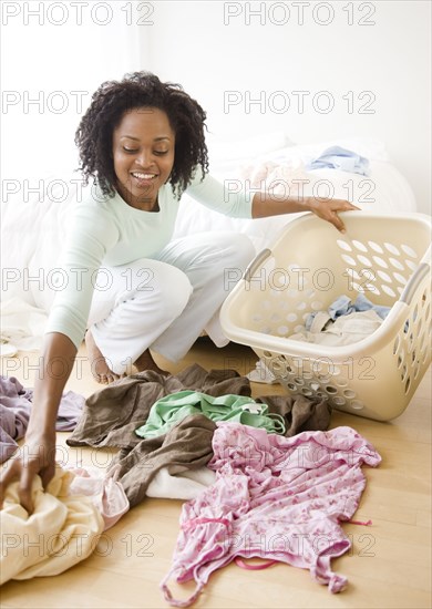 African woman picking up dirty laundry