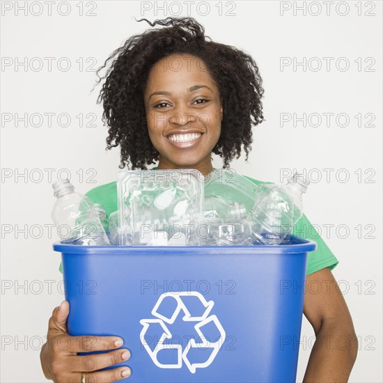 African woman holding recycling bin