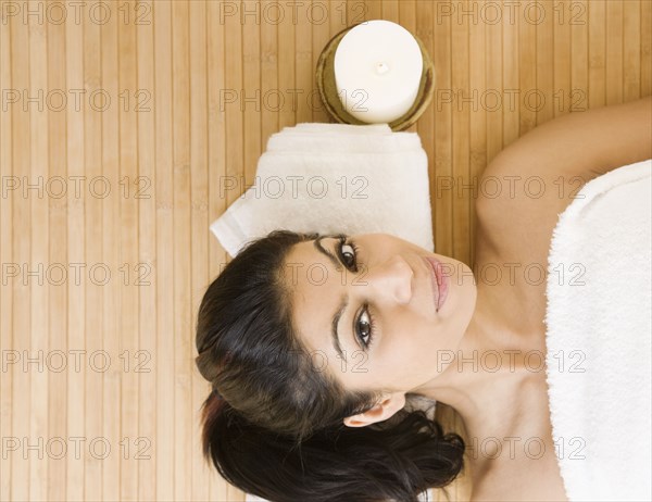 Mixed Race woman laying next to lit candle