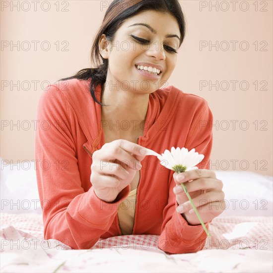 Mixed Race woman pulling petals off flower