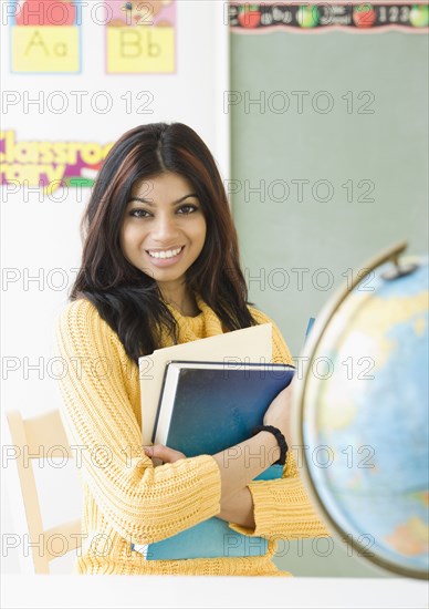 Mixed Race female teacher holding books