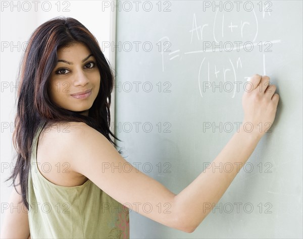 Mixed Race woman writing on blackboard