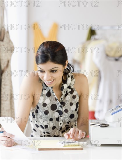 Mixed Race female sales clerk adding receipts