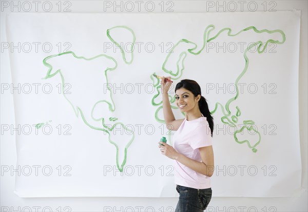 Mixed Race woman painting world map