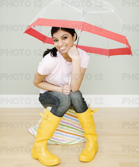 Mixed Race woman with umbrella and rain boots
