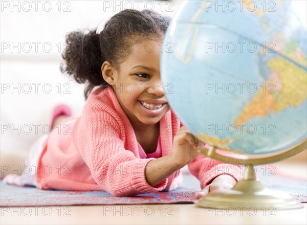 Mixed race girl looking at globe