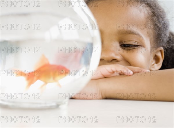 Mixed race girl looking at goldfish