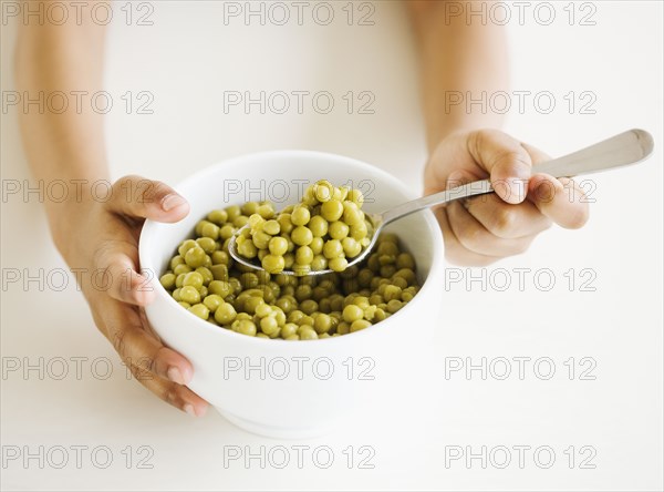 Close up of mixed race girl eating bowl of peas